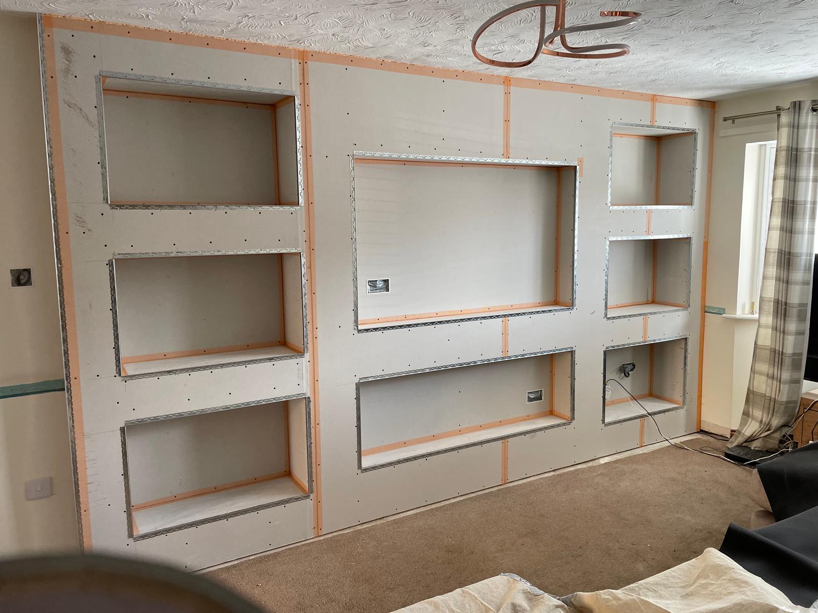 Media wall under construction with recessed shelving niches in fresh plasterboard