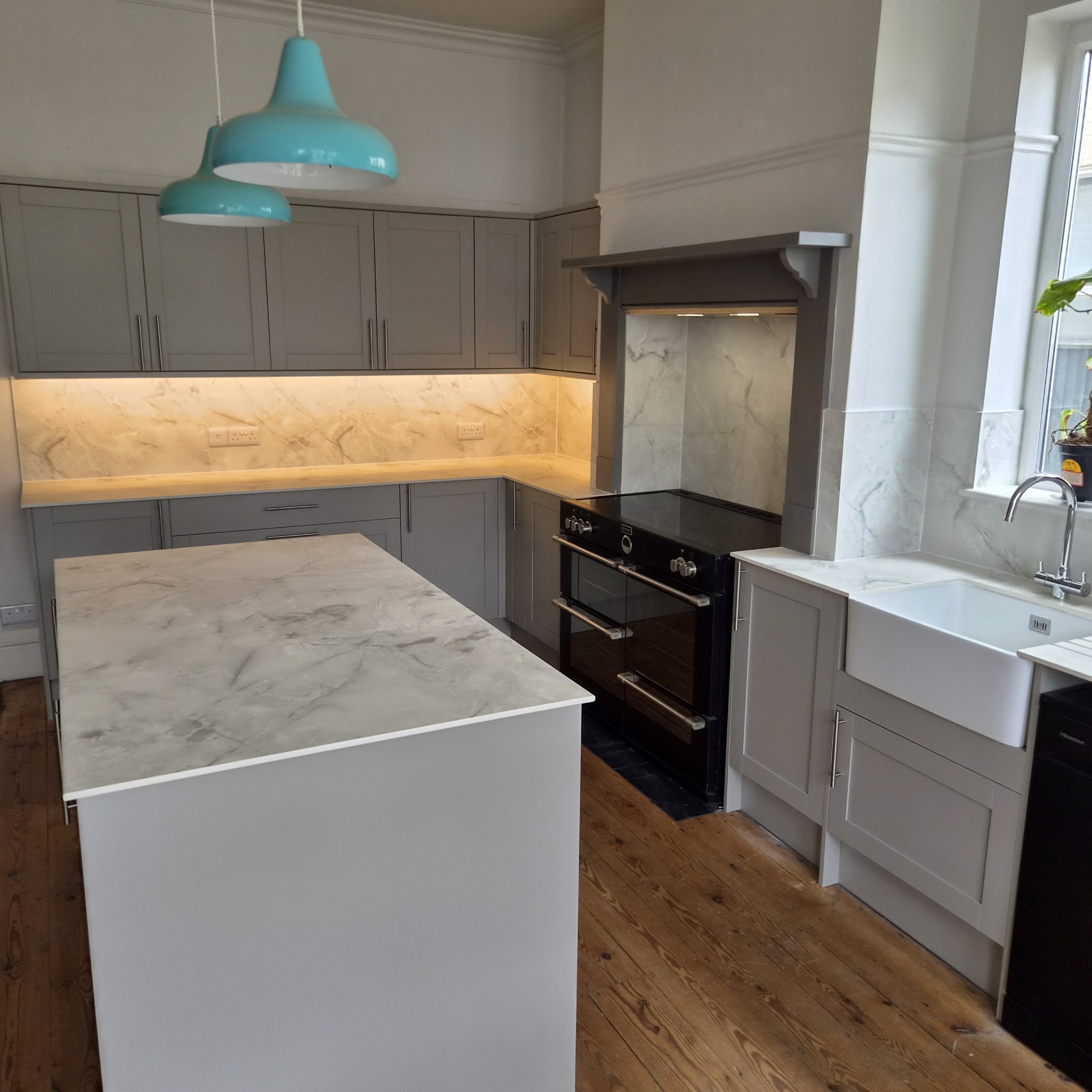 Grey shaker kitchen with a marble-effect island, belfast sink and range cooker