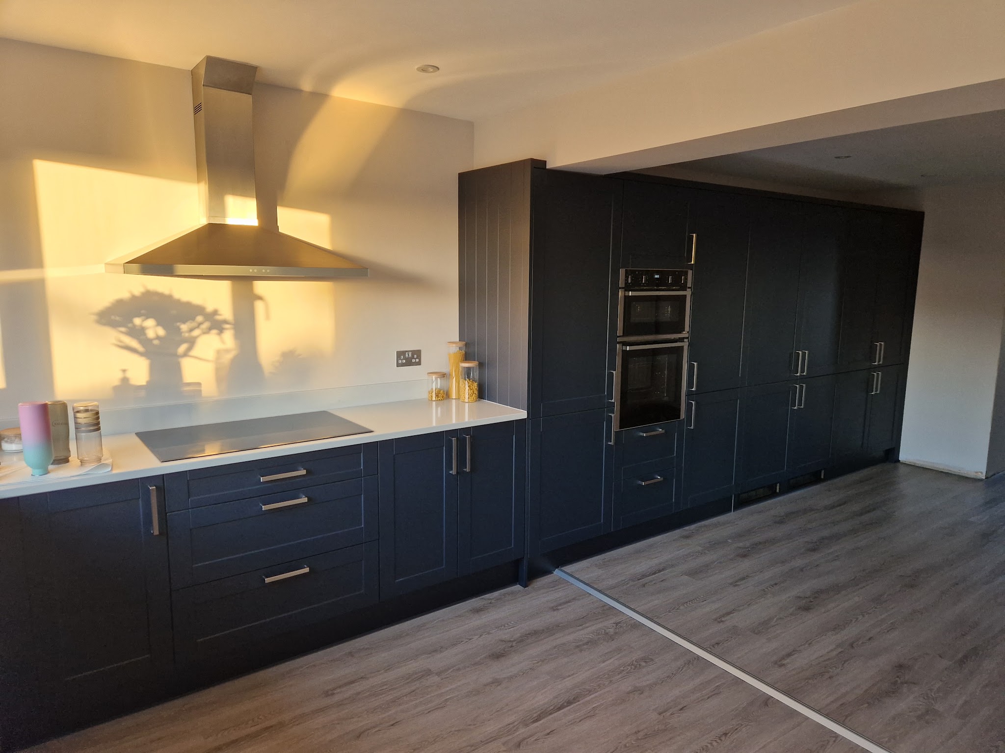 Long navy shaker kitchen with a stainless steel extractor and double ovens