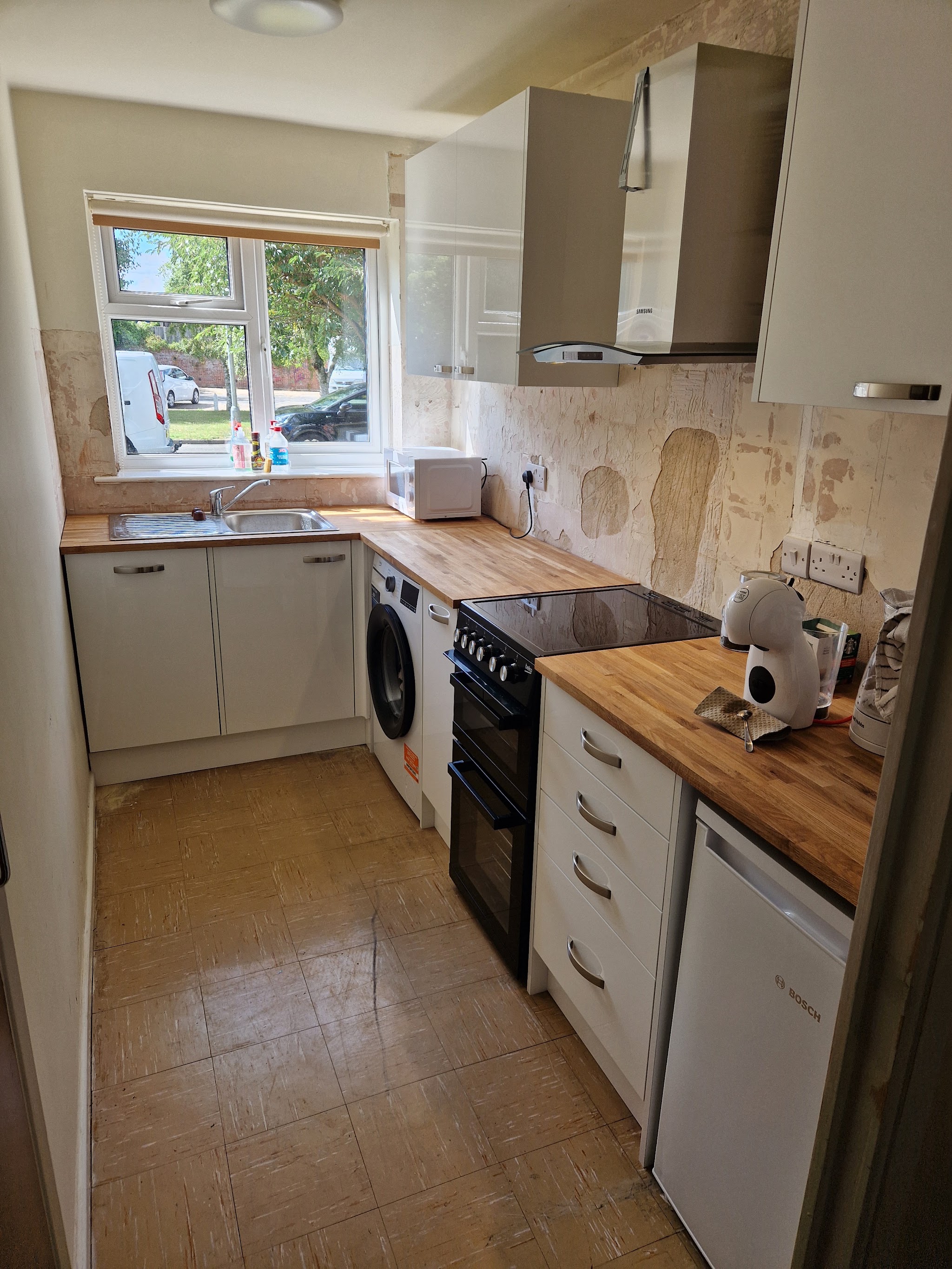Compact kitchen with cream units and a wooden worktop